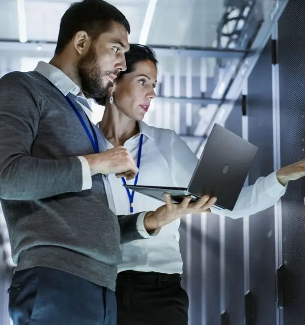 Two people are holding a laptop in front of each other.